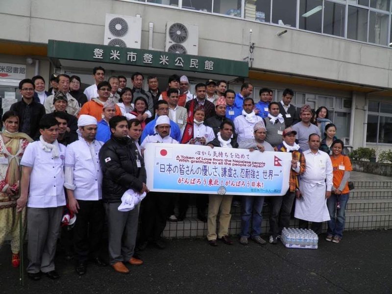 宮城県登米市で、「がんばろう東北！」の横断幕を囲む在日ネパール人